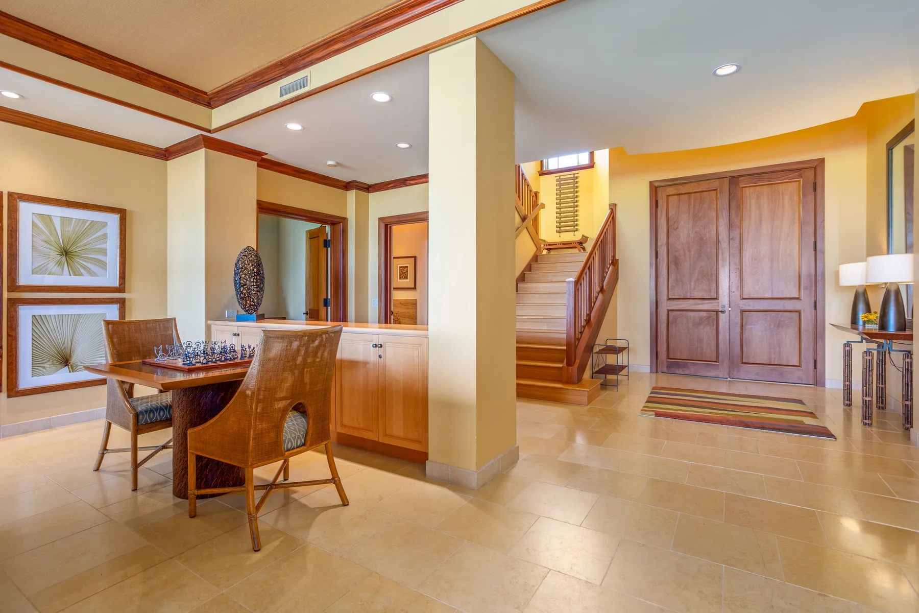 An open entry hall with a staircase, paneled doors, and a dining table.
