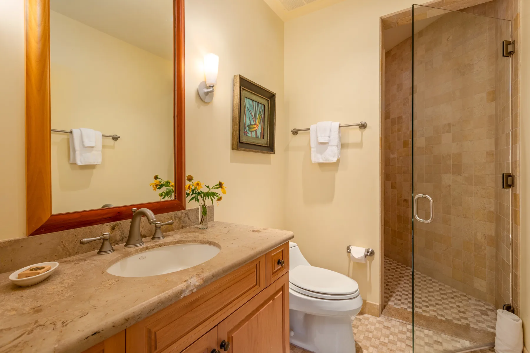 A bathroom with a vanity, toilet, and glass shower.