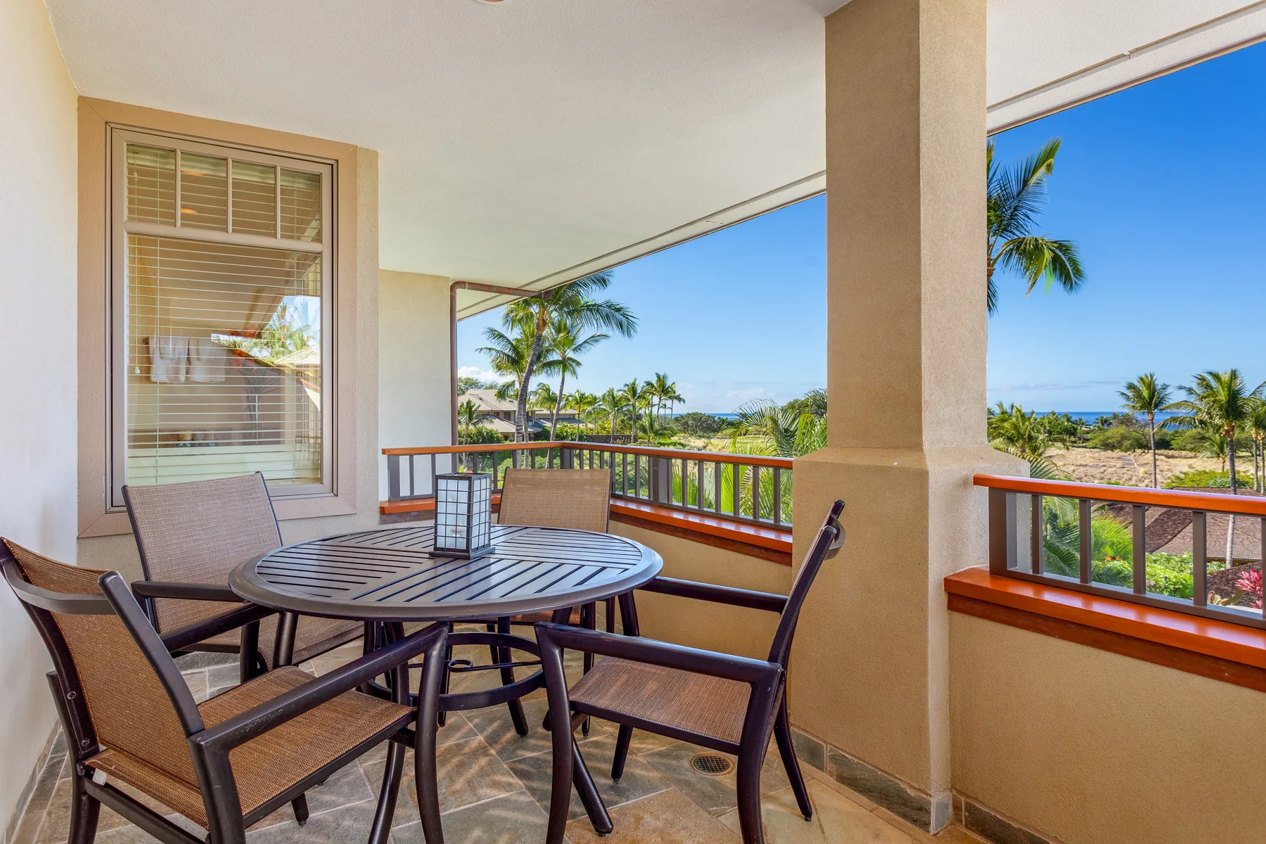 A covered outdoor dining area overlooks palm trees and the ocean.