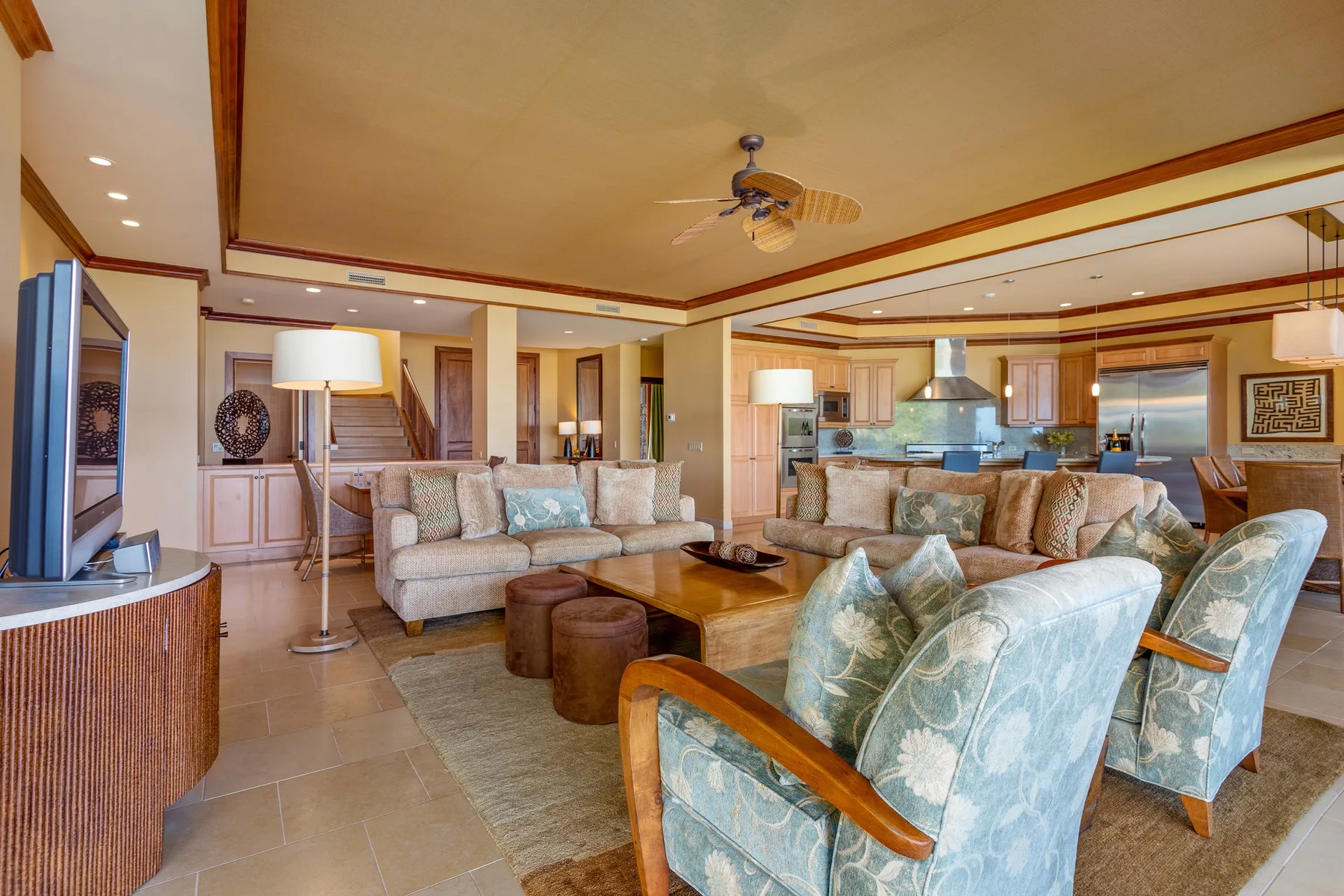 A spacious living room with upholstered seating, a coffee table, and an open kitchen.