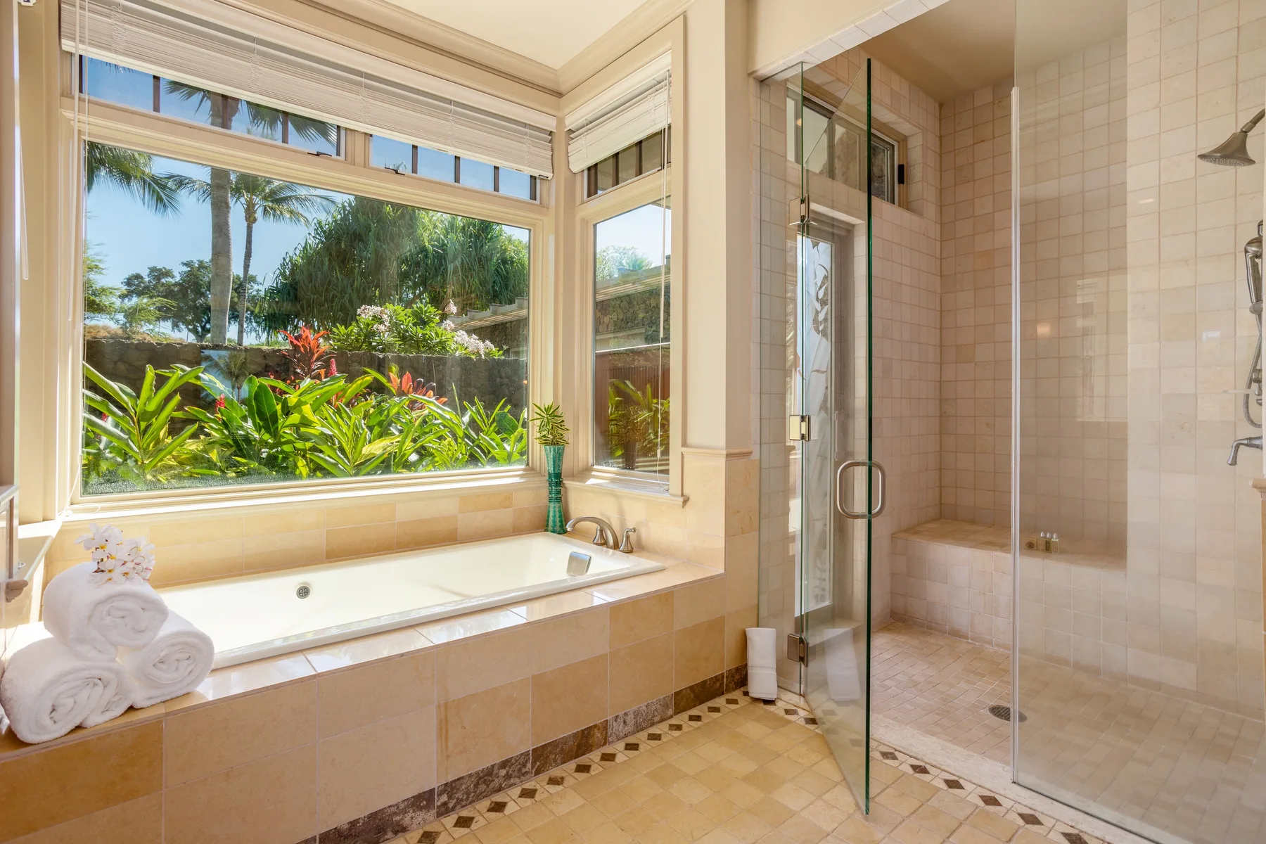 A bright bathroom with a bathtub beside a glass-enclosed shower and garden-facing windows.