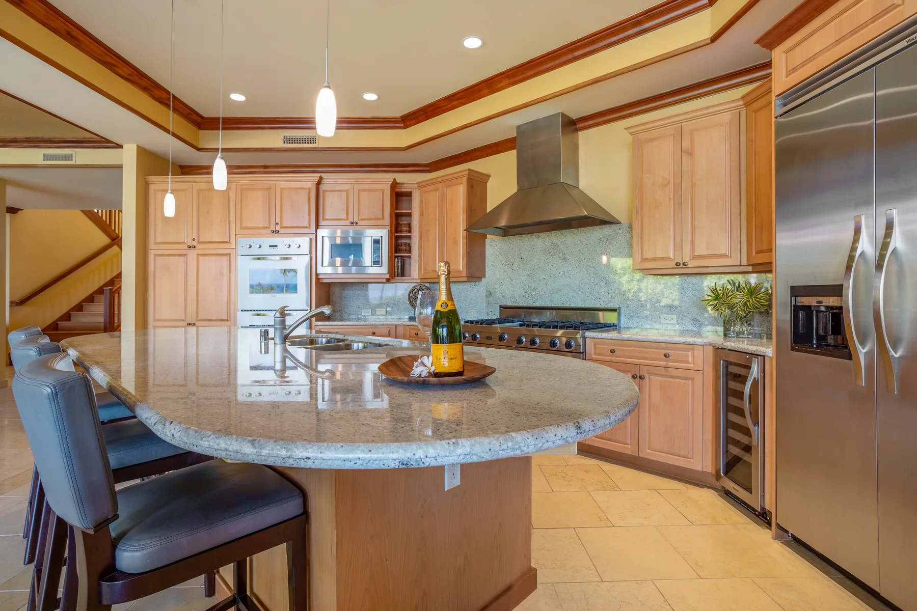A spacious kitchen with a central island, wooden cabinets, and stainless steel appliances.