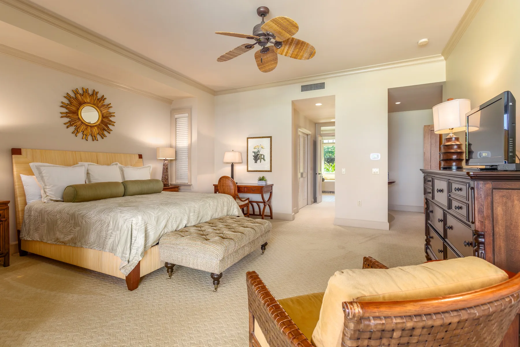 A bedroom with a large bed, a cushioned bench, and a ceiling fan.