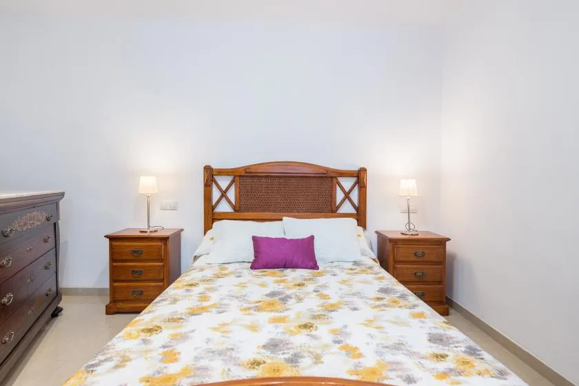 A bedroom with a wooden bed, floral bedding, and matching bedside tables.