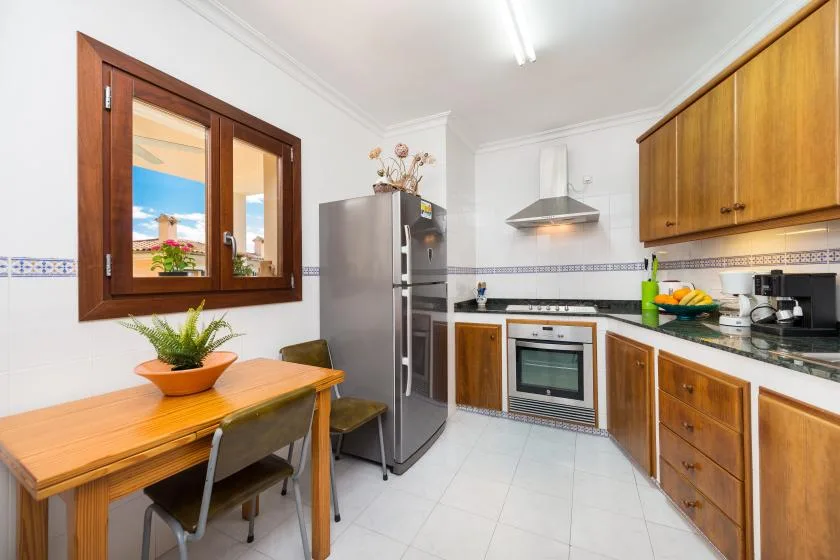 A kitchen with wooden cabinets, stainless steel appliances, and a small dining table.