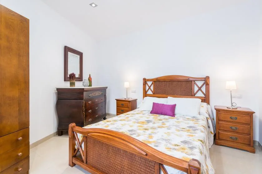 A bedroom with a wooden bed, patterned bedding, and matching bedside tables.