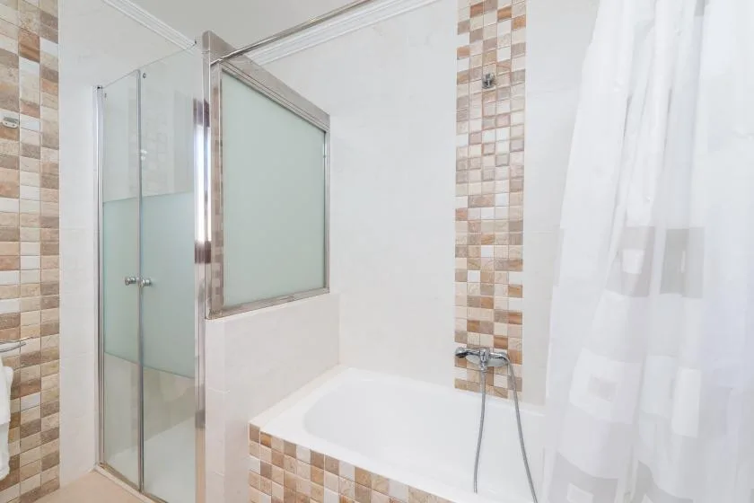 A bathroom with a bathtub, tiled surround, and shower curtain.