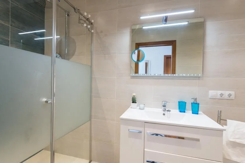 A bright bathroom with a glass shower and a white vanity beneath a mirror.