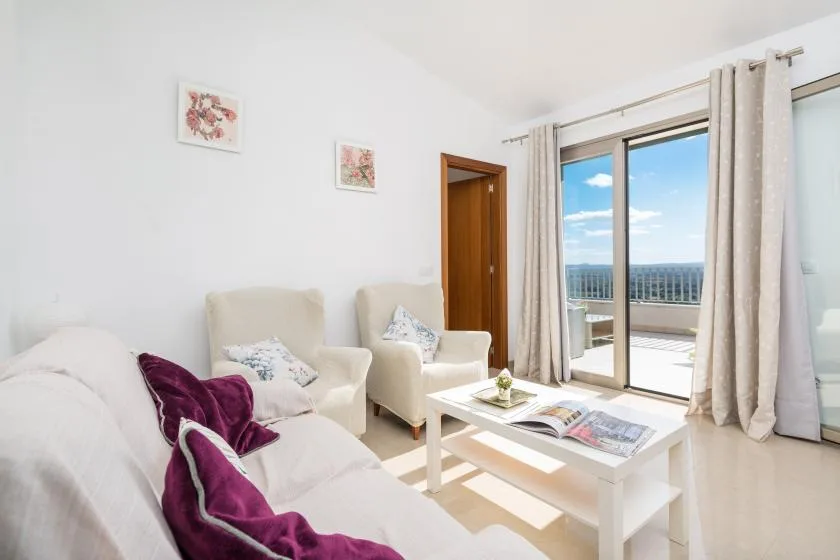 A bright living room with seating, a coffee table, and doors opening onto a balcony.