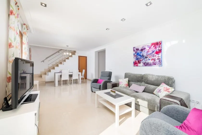 A bright living room with gray seating, a white coffee table, and a staircase.