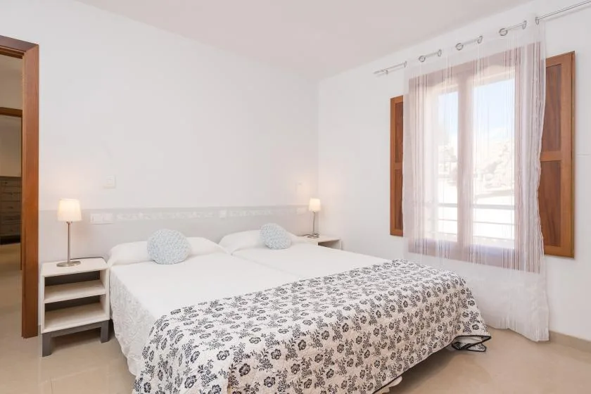A bright bedroom with white bedding and a patterned coverlet.