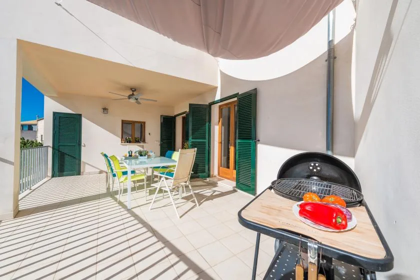 A sunny patio with an outdoor dining table and a barbecue grill.