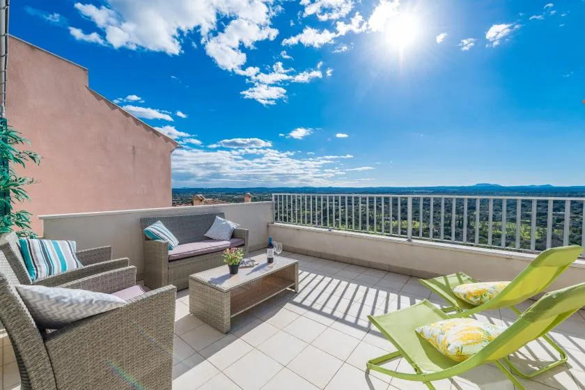 A sunny rooftop terrace with outdoor seating and an open view beyond the railing.