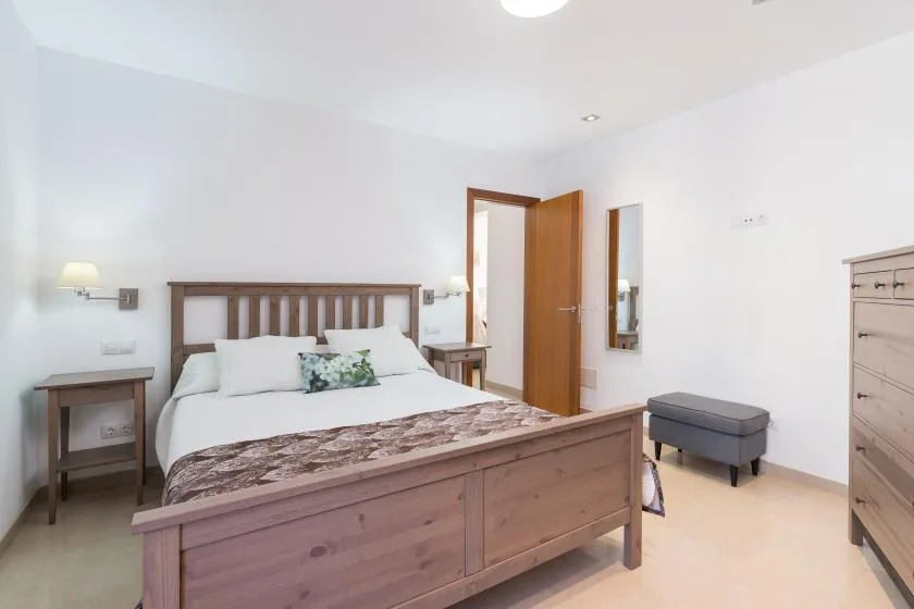 A bedroom with a double bed, bedside tables, and a wooden dresser.