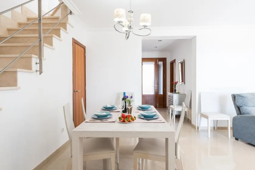 A bright dining area with a set table beside a staircase.