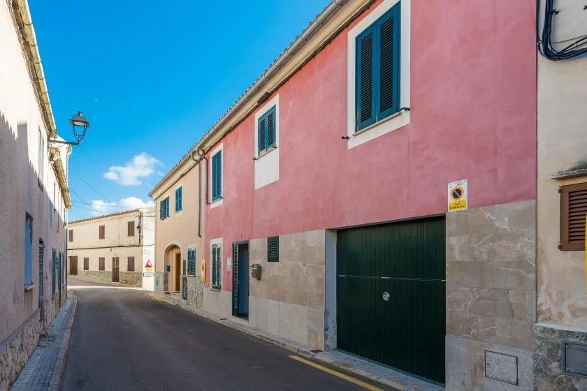 A narrow street runs between pastel-colored buildings beneath a clear blue sky.