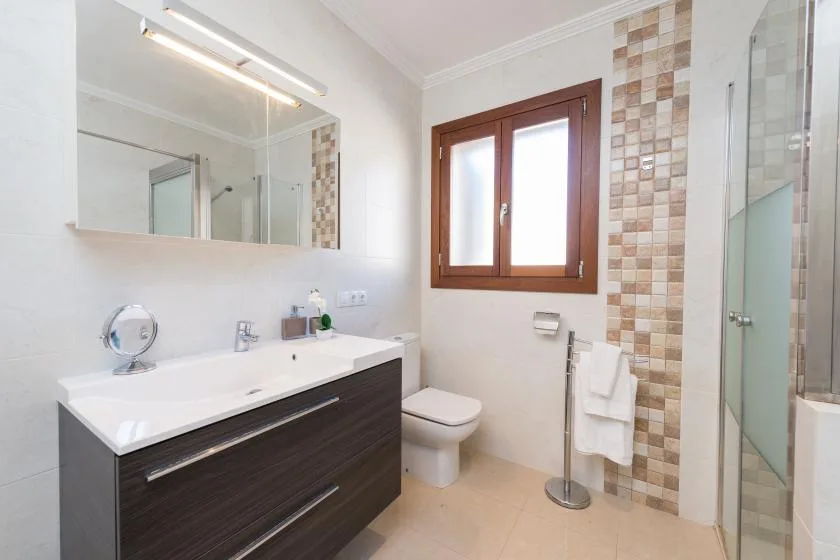 A bright bathroom with a wide vanity, mirror, and glass shower.