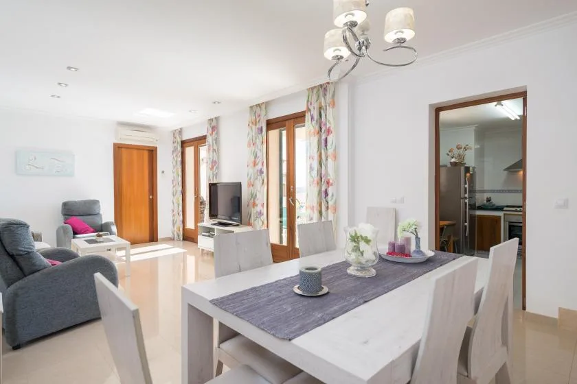A bright living and dining area with a table, seating, and windows.