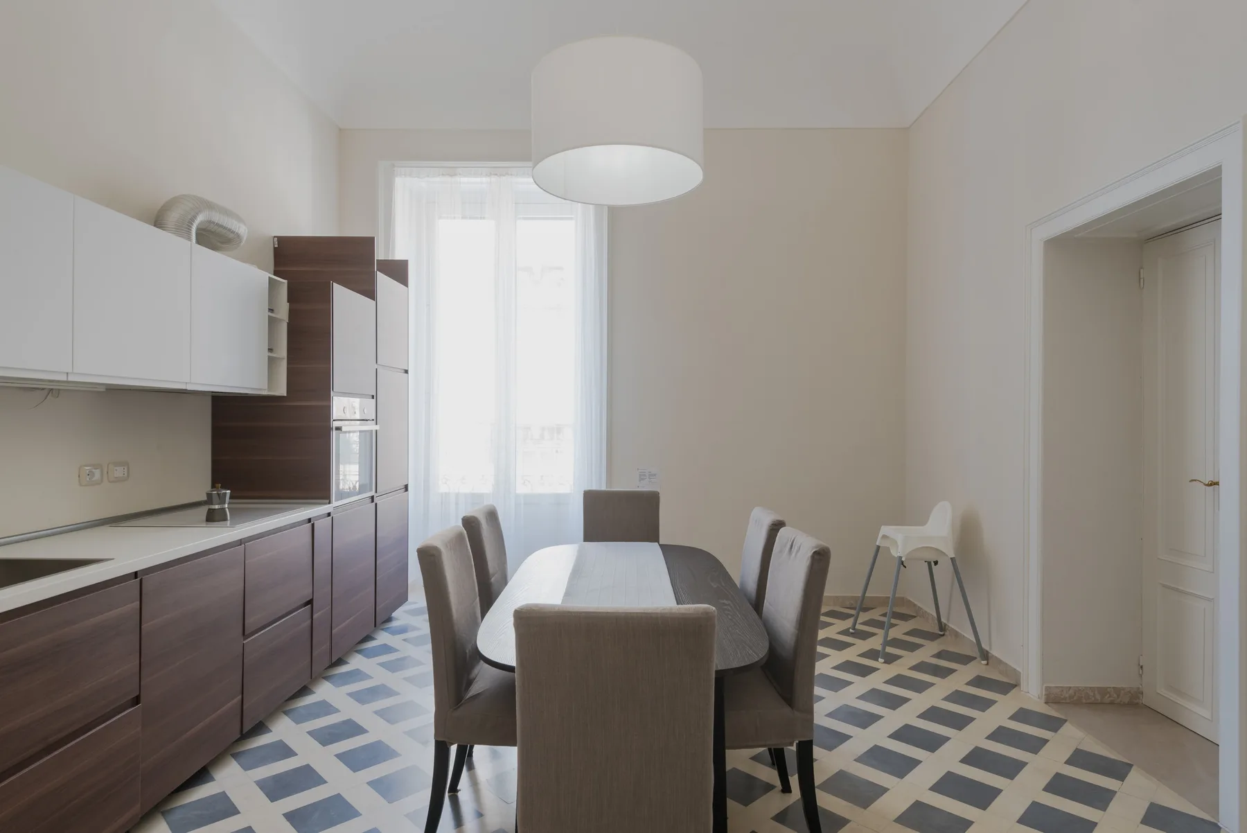 Un comedor con mesa y sillas junto a una cocina compacta.