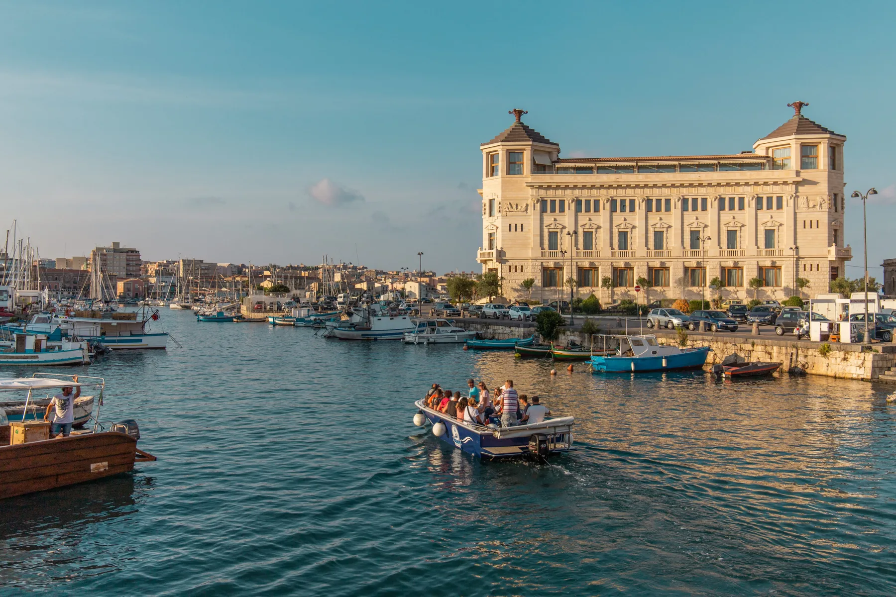 Un puerto con barcos en el agua y un gran edificio frente al mar.