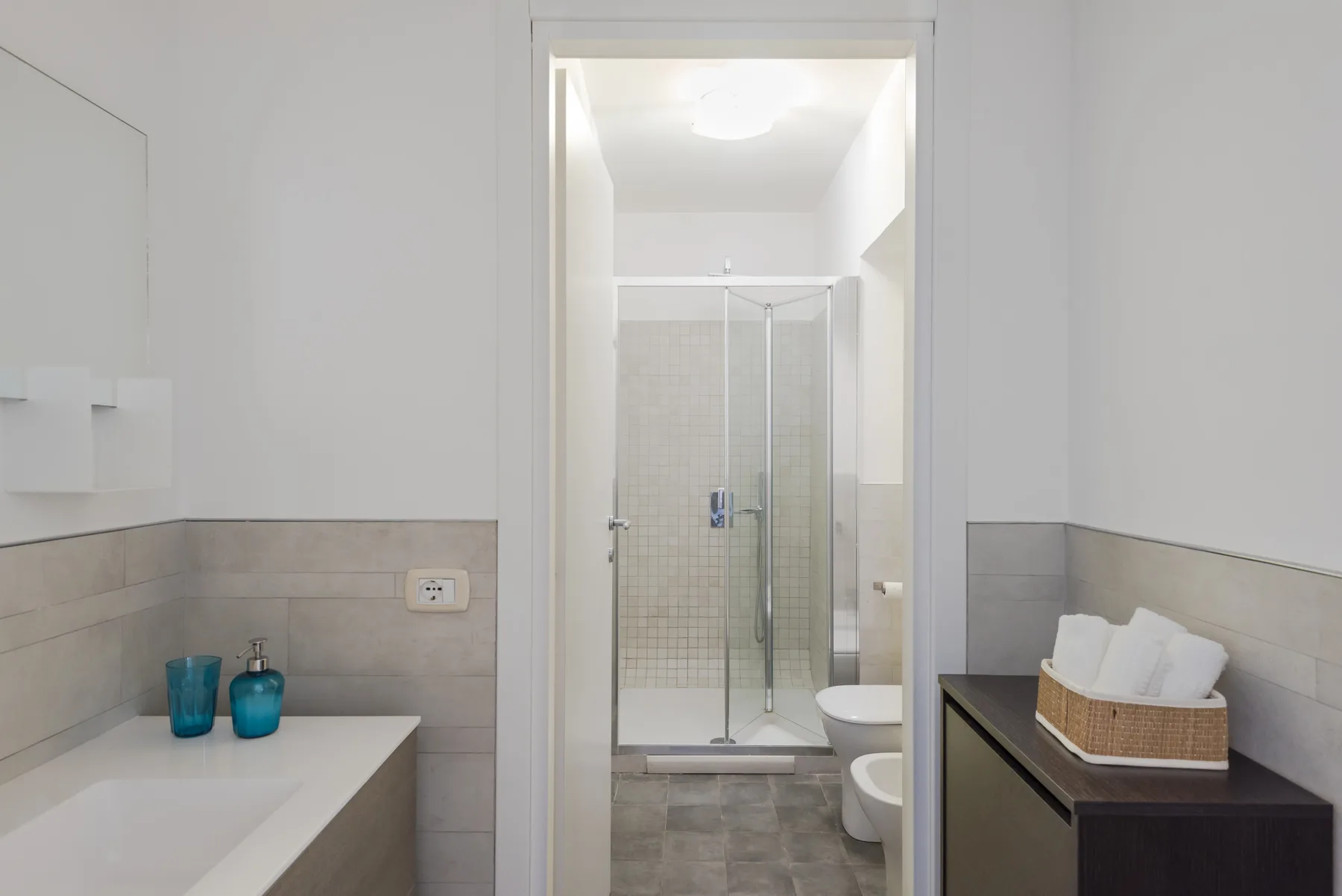 Un baño con lavabo y una ducha con mampara de vidrio.