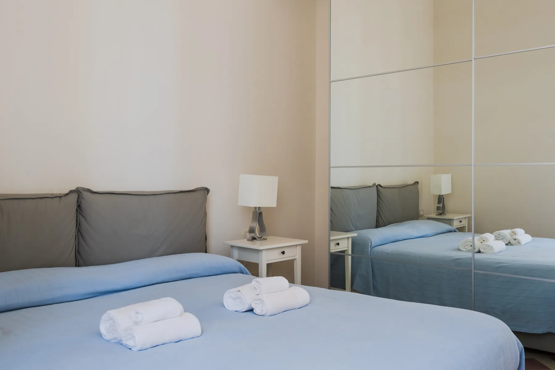 Un dormitorio con una cama, toallas dobladas y una mesita de noche.