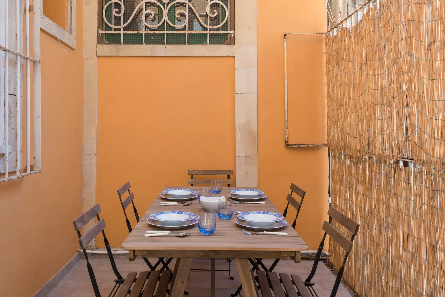 Un comedor al aire libre con una mesa larga preparada para comer.