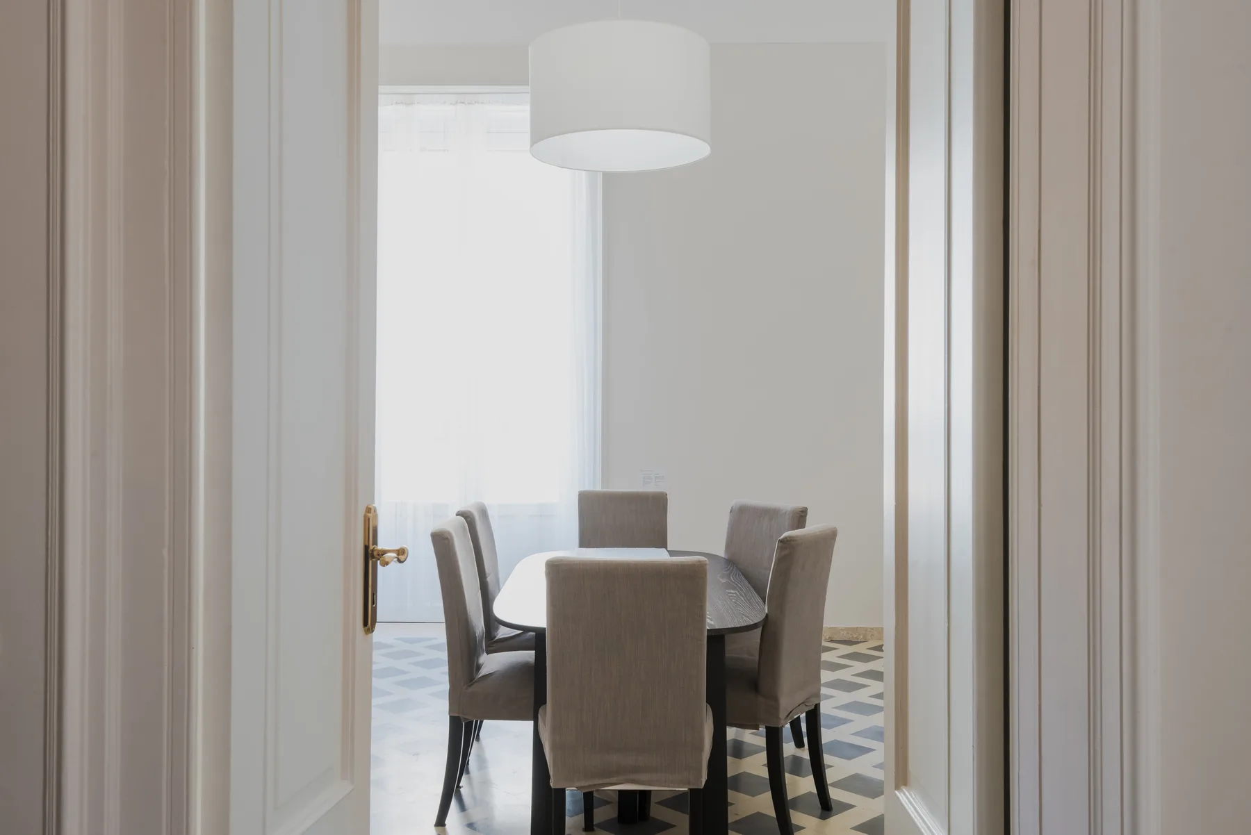 Comedor con una mesa y asientos tapizados bajo una lámpara colgante.