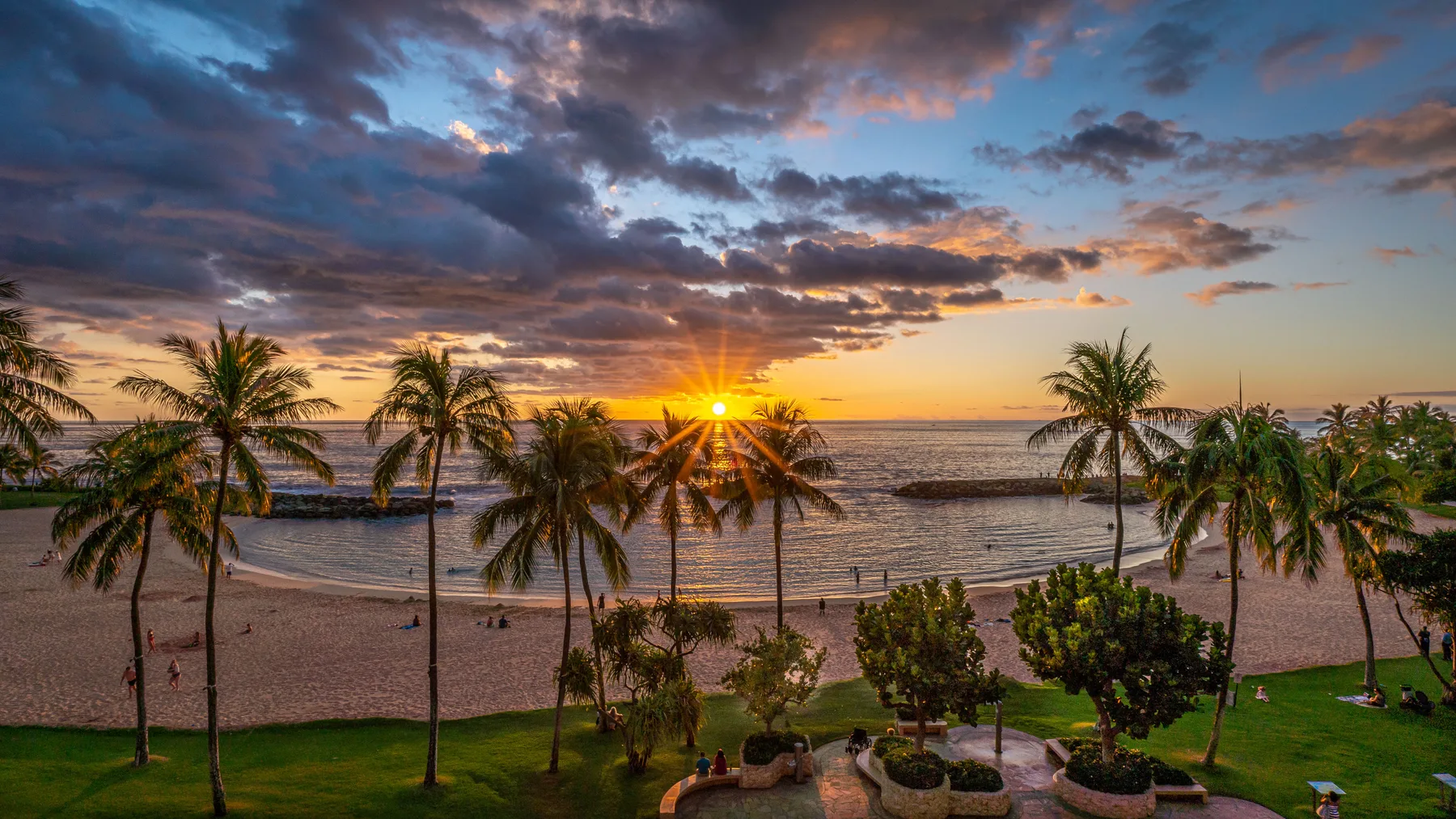 Una playa tropical al atardecer, con palmeras a lo largo de la costa.