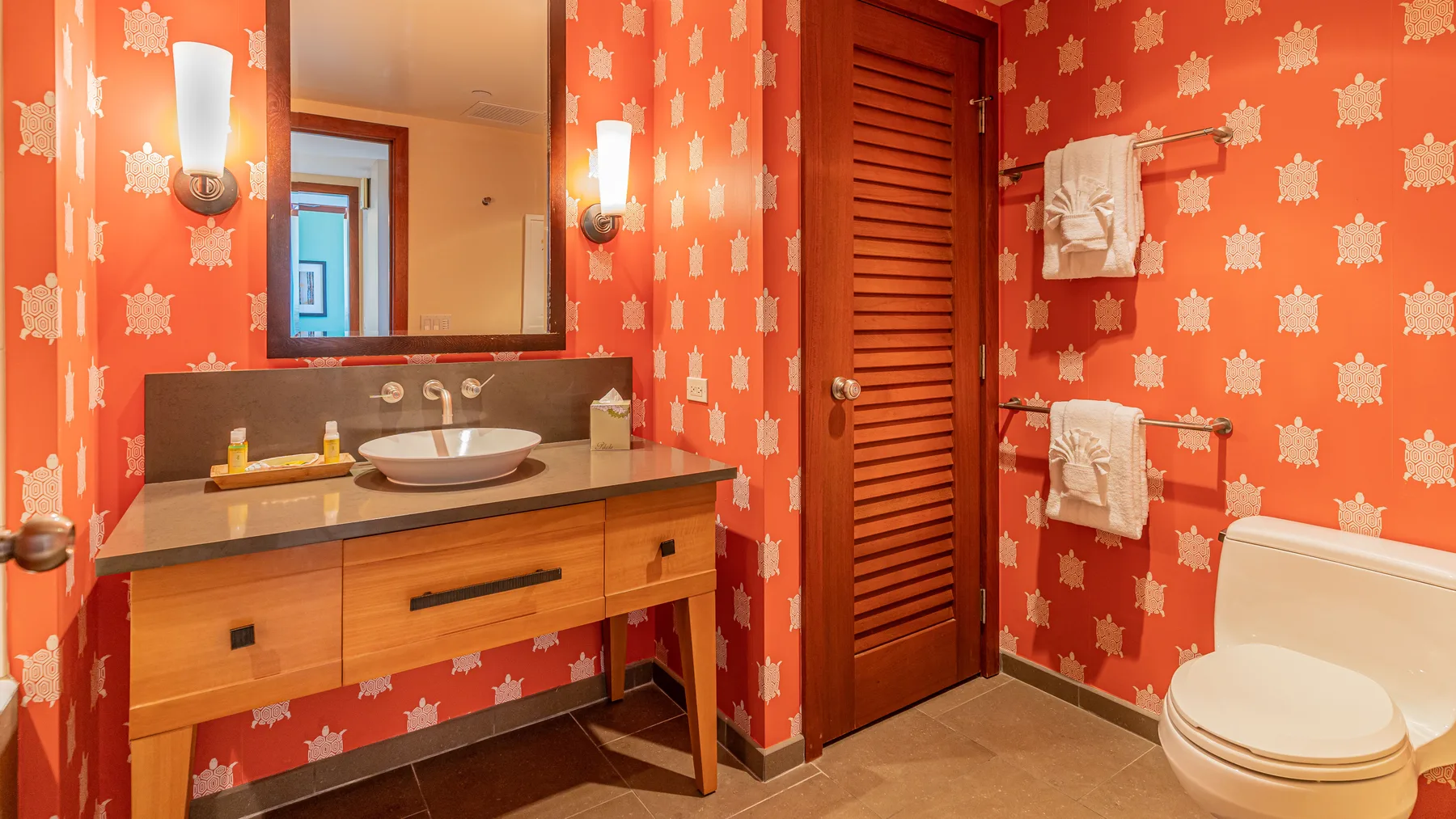 Un tocador de baño con lavabo y espejo junto a un inodoro.