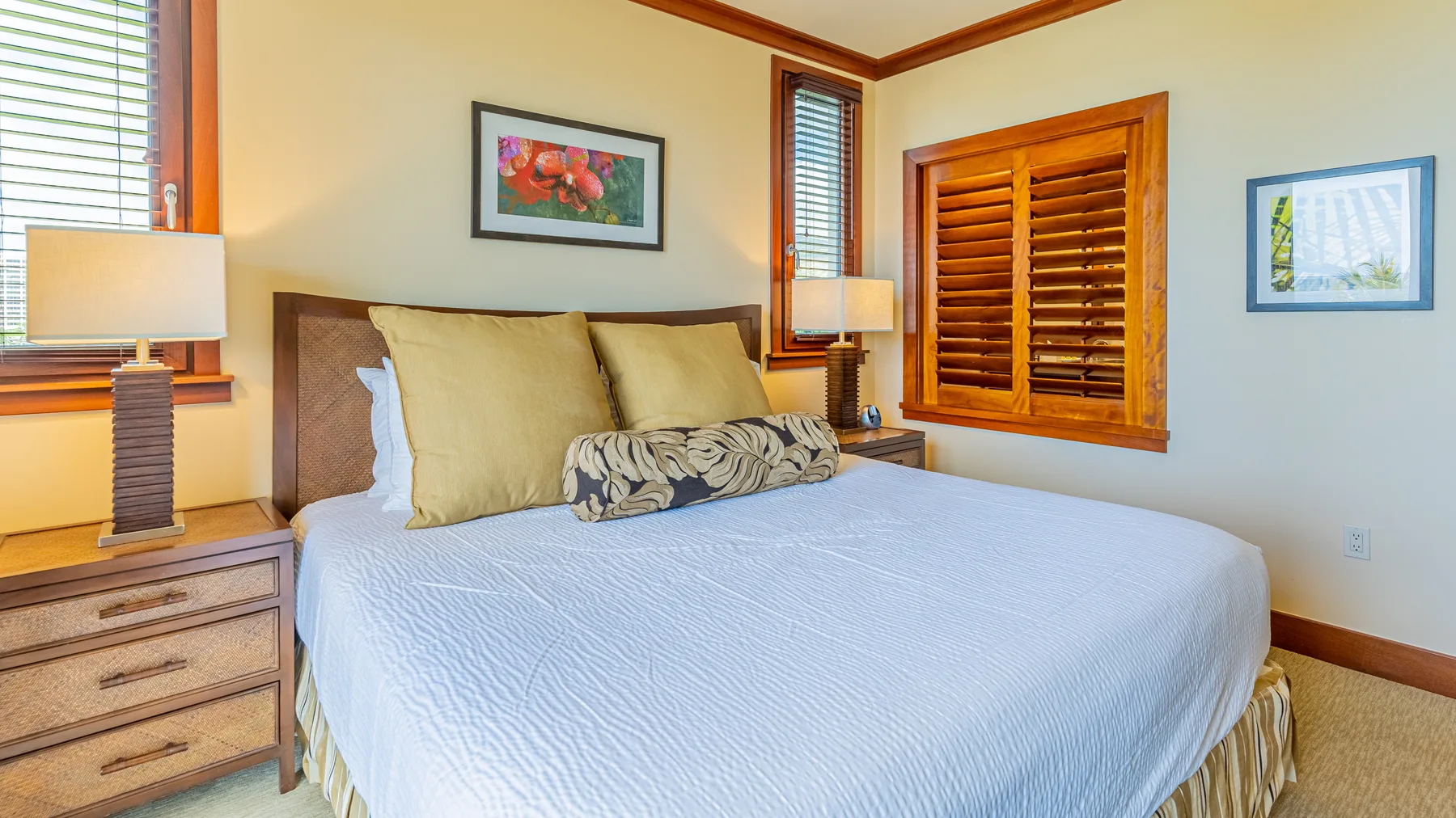 Un dormitorio con una cama grande, mesitas de noche y contraventanas de madera.