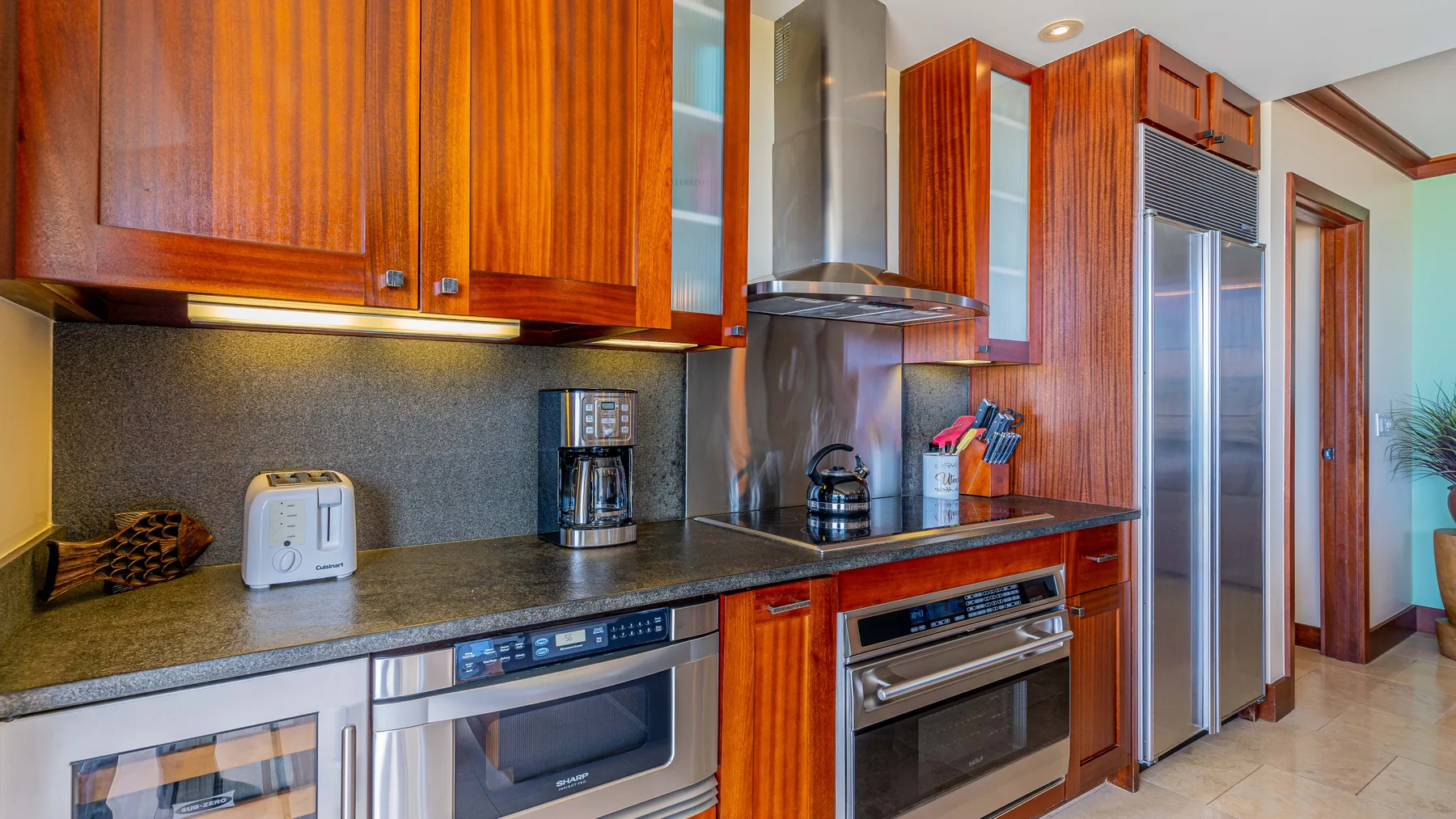 Cocina con gabinetes de madera, una encimera y electrodomésticos de acero inoxidable.