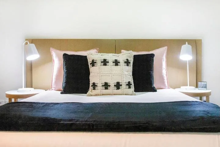 A neatly made bed with decorative pillows and matching bedside lamps.