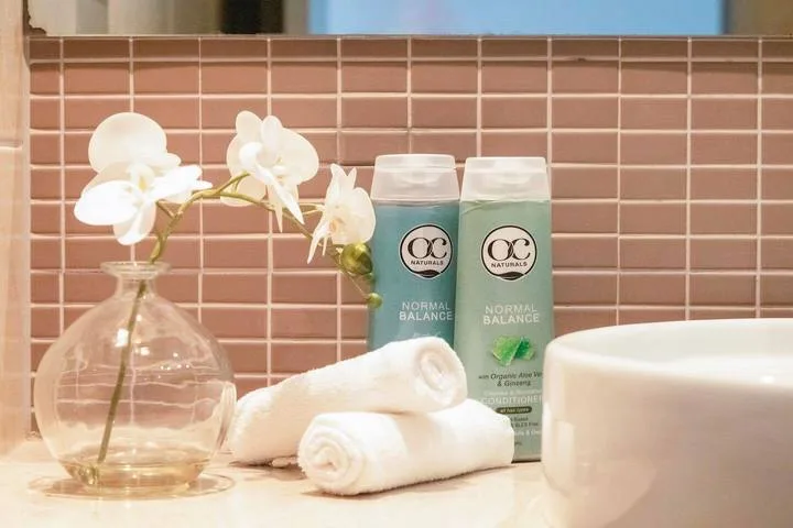 A bathroom vanity displays folded towels, toiletries, and white flowers.