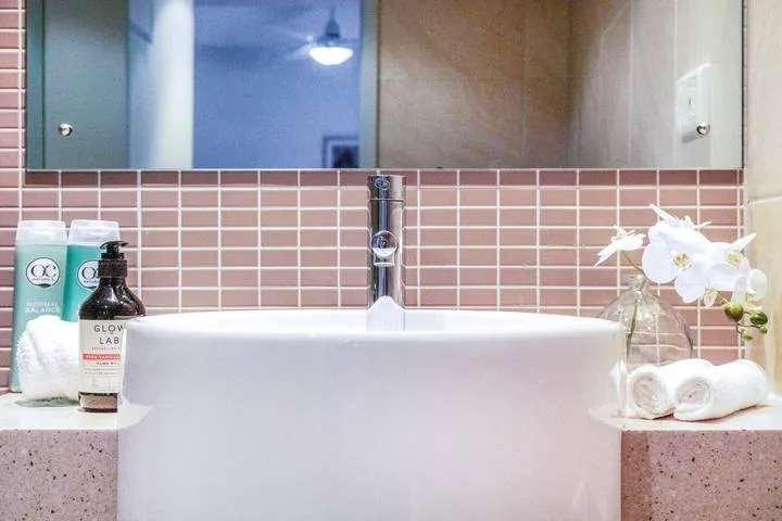 A bathroom vanity with a wide mirror, tiled backsplash, and white basin.