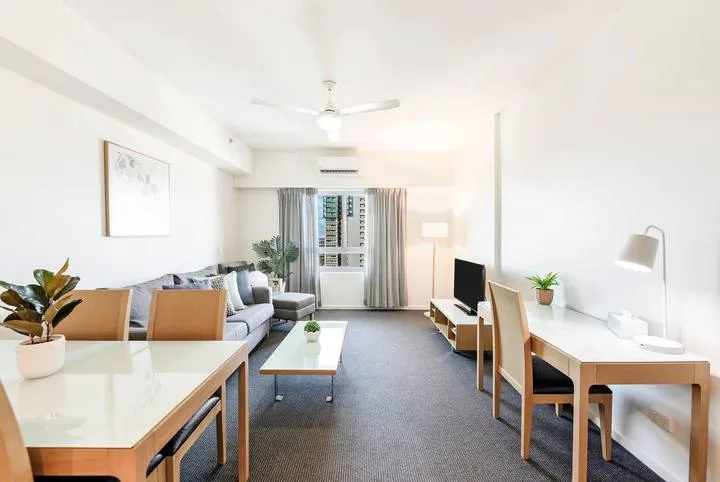 A bright living and dining room with a sofa, table, and desk.