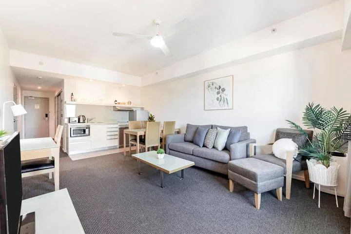 Living room with a gray sofa, coffee table, and open kitchen.