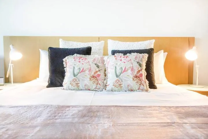 A neatly made bed with floral accent pillows and bedside lamps.