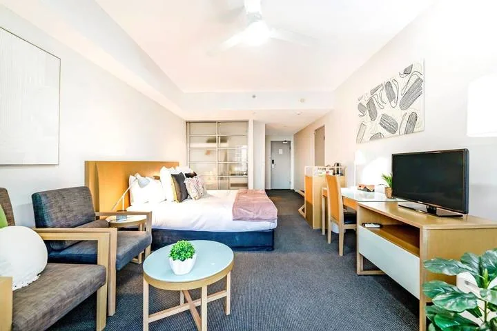 A furnished bedroom with a bed, seating area, and television.
