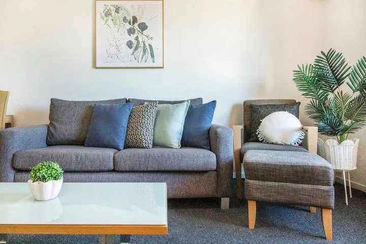 A living room with a gray seating area, cushions, and a glass coffee table.