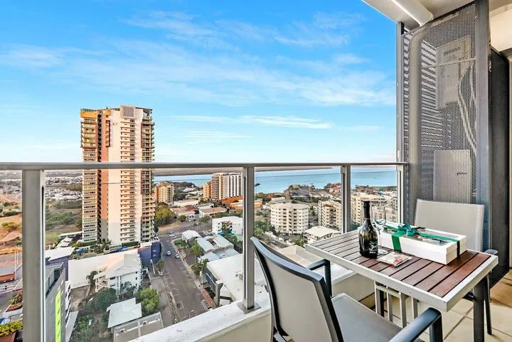 A balcony seating area overlooks nearby buildings and the surrounding city.