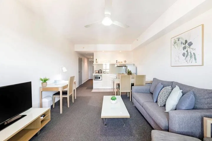 A living room with a sofa, coffee table, and open kitchen.