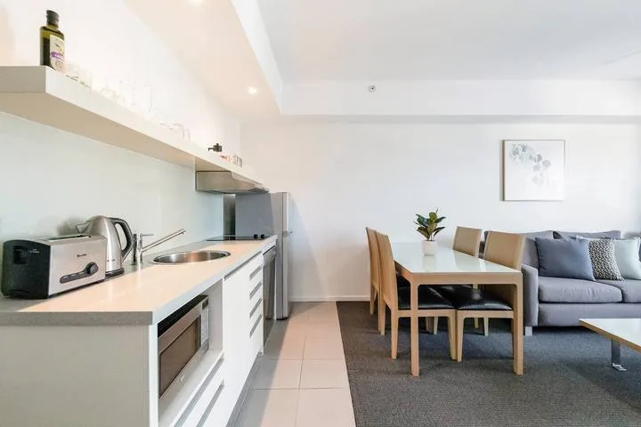 An open-plan kitchen and dining area with a gray sofa beside the table.