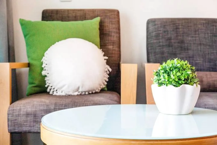 A seating area with dark upholstered chairs, colorful cushions, and a round glass table.