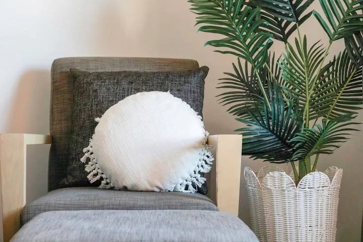 A cushioned chair sits beside a leafy potted plant.