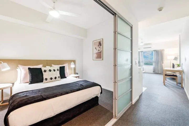 A bedroom with a neatly made bed beside a frosted glass partition.