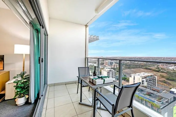 A balcony dining area with a table and chairs overlooking the city.