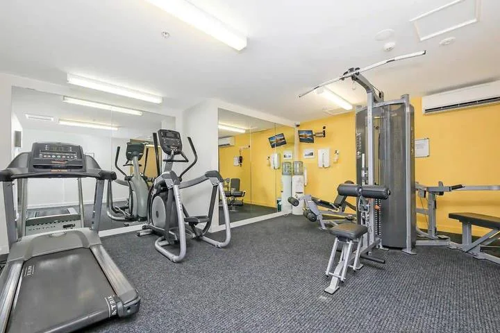 A fitness room with treadmills, elliptical machines, and weight equipment.