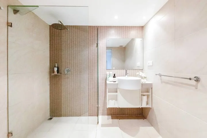 A bright bathroom with a glass shower and a sink beneath a mirror.