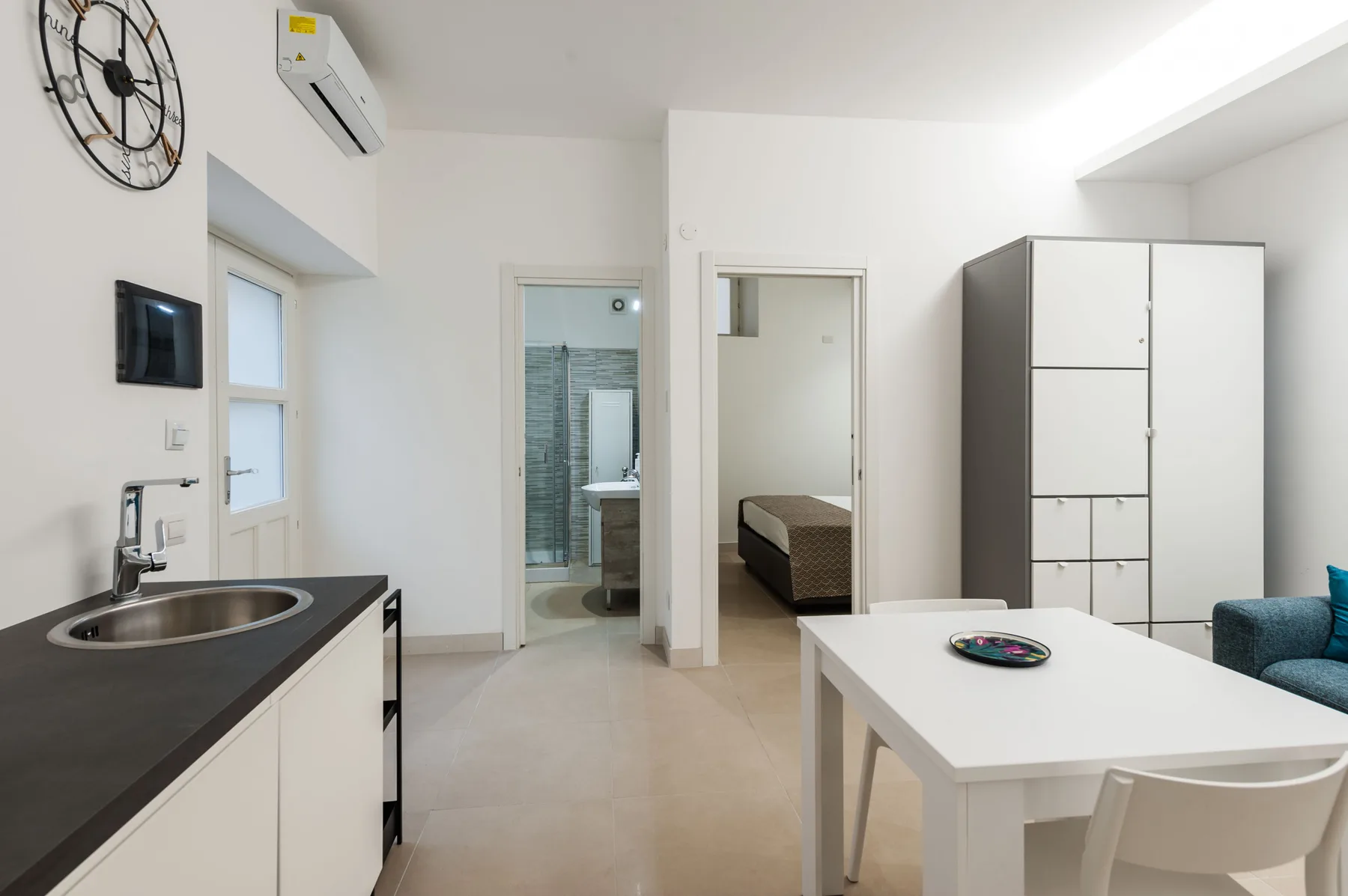 Una estancia luminosa con una mesa de comedor y puertas abiertas hacia un dormitorio y un baño.